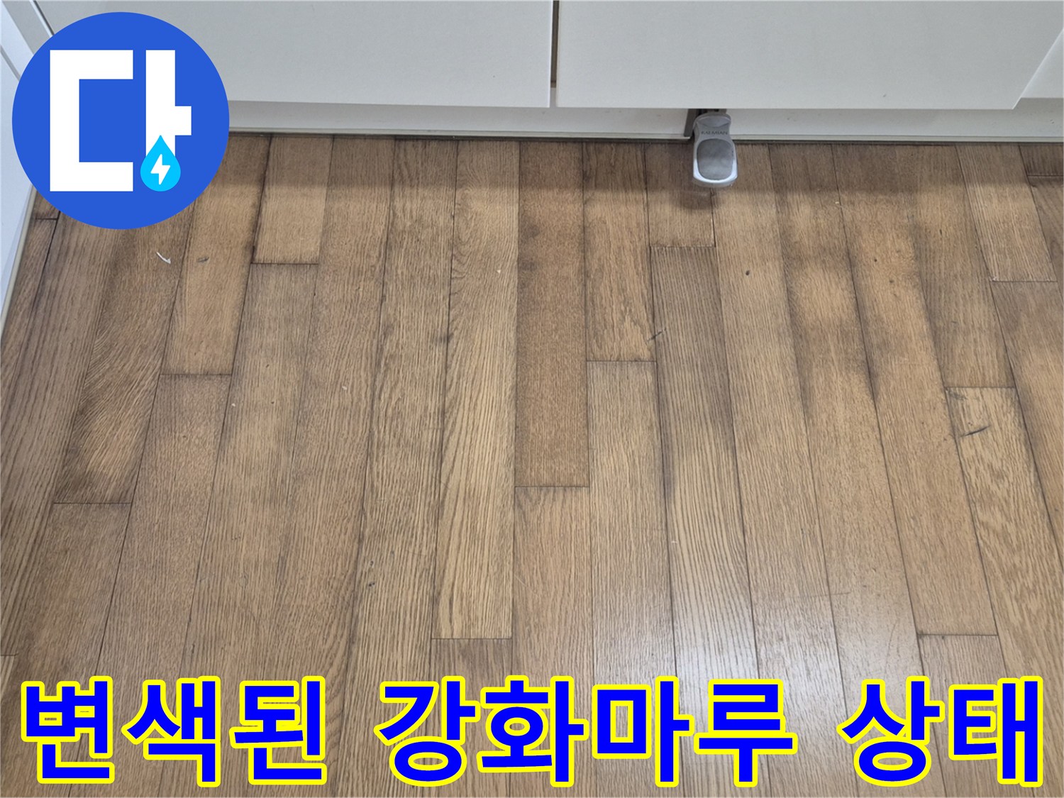 싱크대 하단부의 짙게 변한 마루 표면을 근접 촬영한 사진입니다.