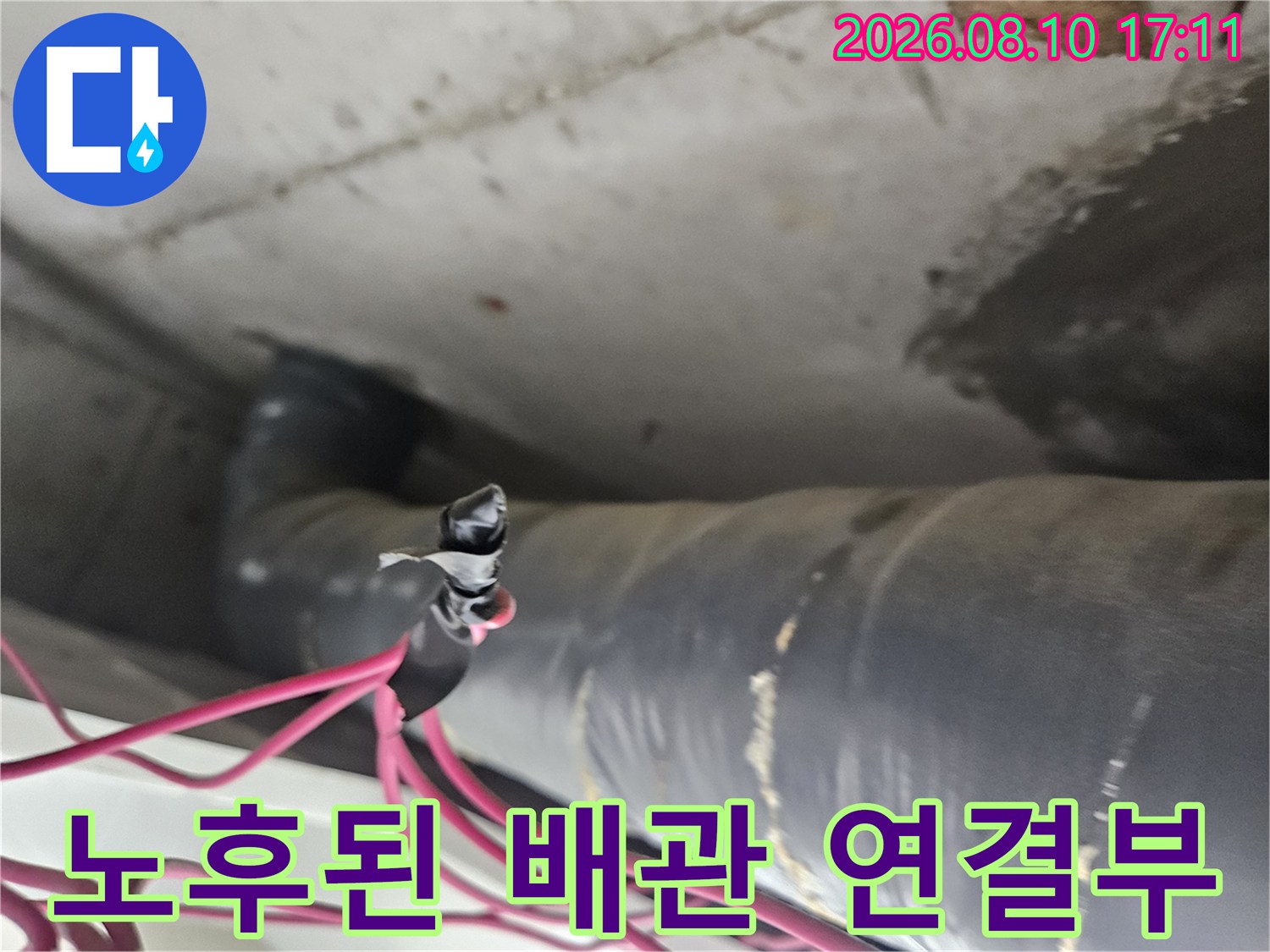 천장 내부의-노후된 배관 연결 부위와 전선이 겹쳐진 모습입니다.