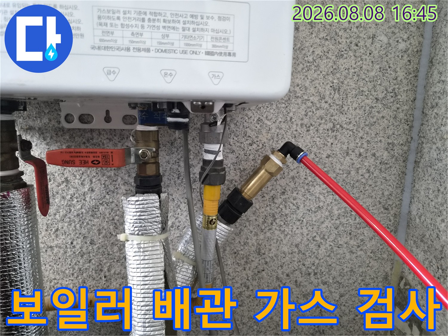 보일러 하단부의 은박 보온재 배관과 탐지용 호스가 연결된 사진입니다.