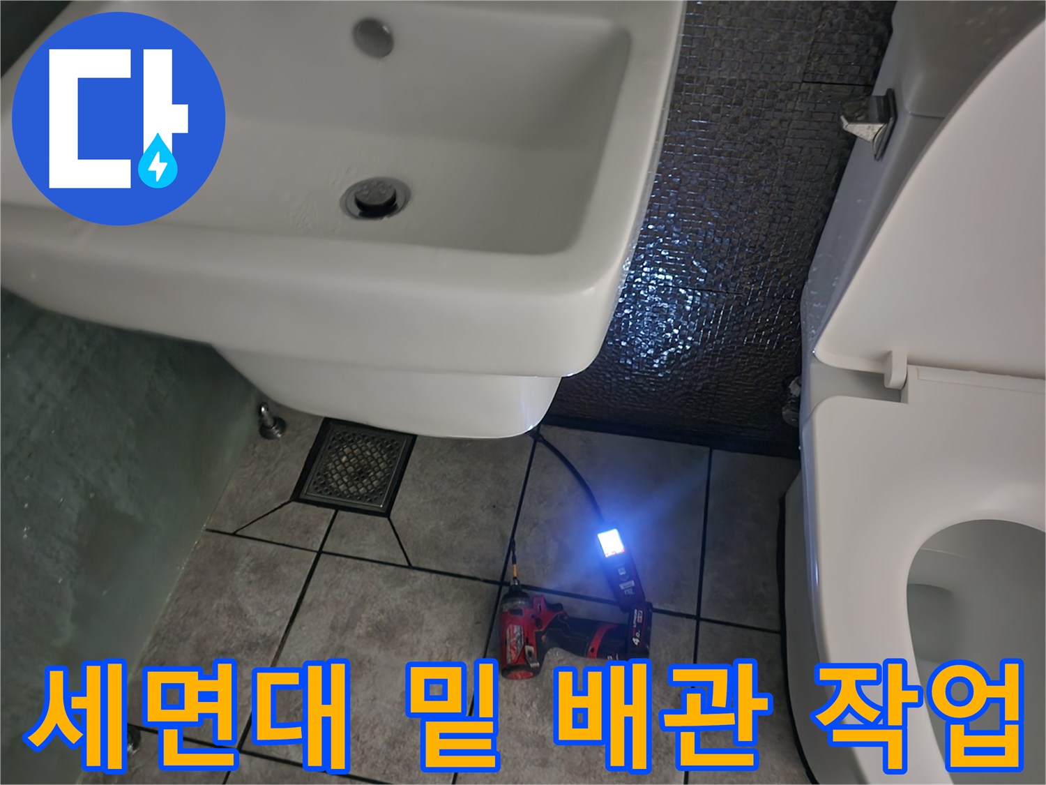 작업용 전동 드릴과 라이트가 배치된 세면대 하단 화장실 현장