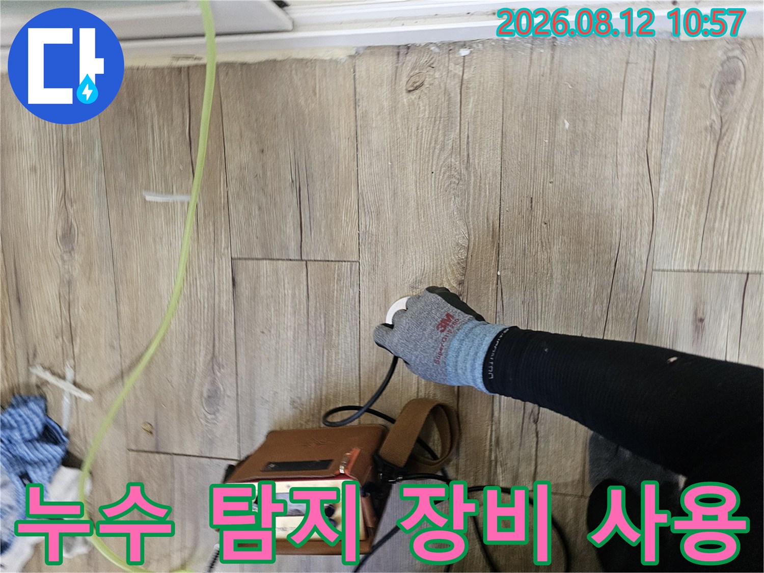 나무 바닥재 위에서-누수 탐지기를 사용하여 배관을 점검하는 모습