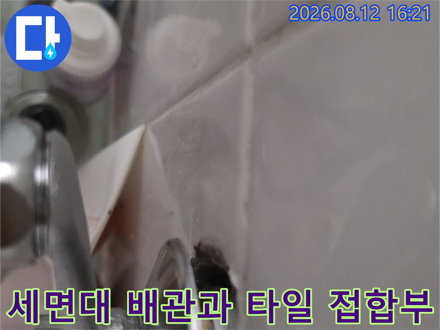 금속 재질의 세면대 배관이 벽 타일에 연결된 부위-누수 지점 근접 사진