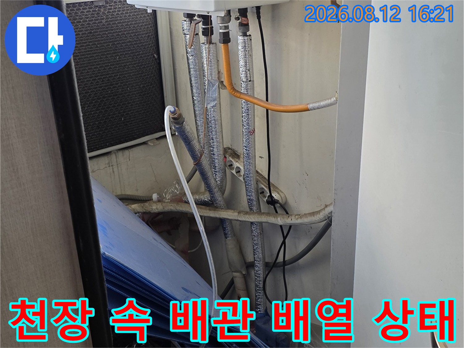 천장 마감재 안쪽으로 설치된 흰색 보일러와 은색 보온재가 입혀진 배관 라인들