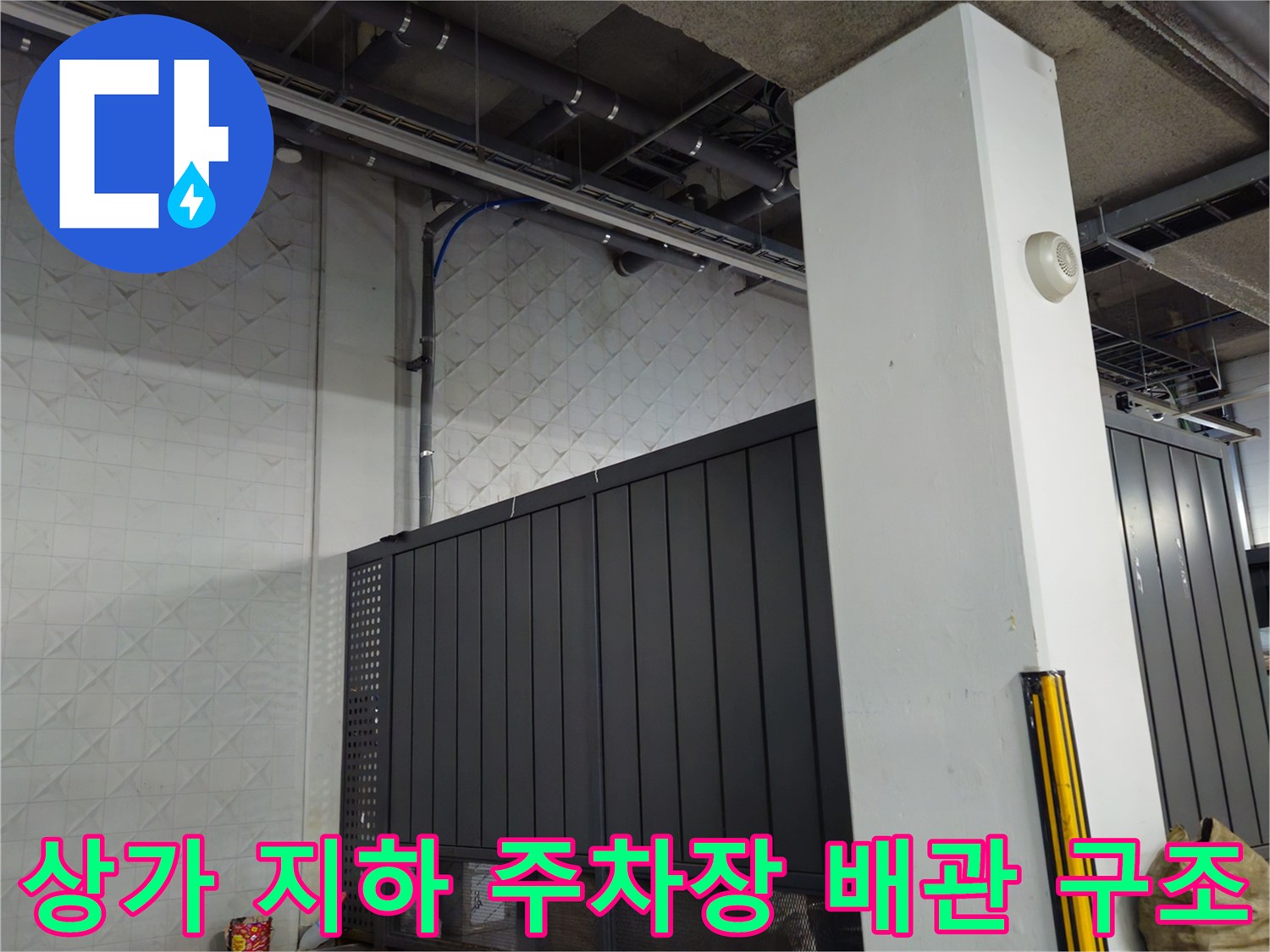 지하 주차장 천장의-노출된 배관과 벽면 패널 모습