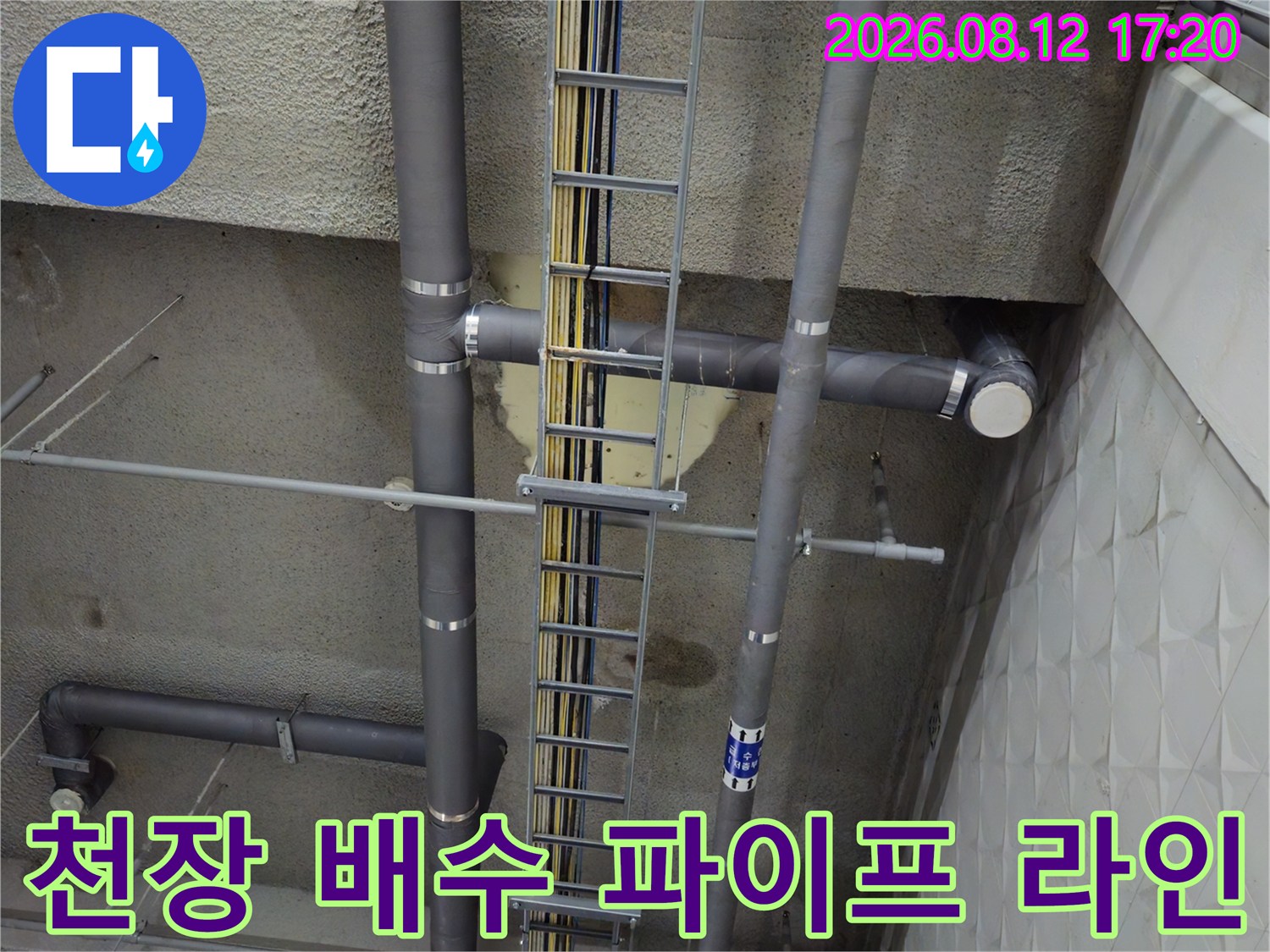 회색 PVC 관과 케이블 트레이가 설치된 지하주차장 천장 구조물입니다.