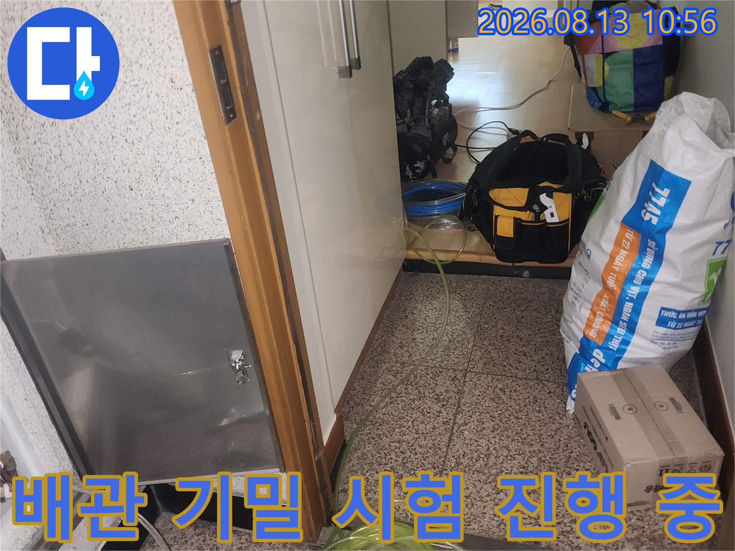 점검구 내부의 배관에 노란색 튜브와 측정기가 연결되어 있는 누수 탐지 장면