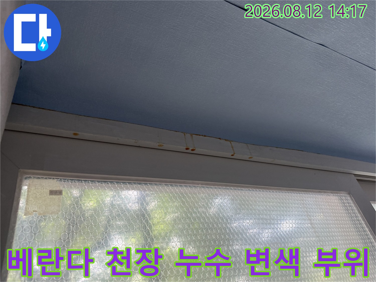푸른색 베란다 천장재와 몰딩 접합부에 발생한 갈색의 누수 오염 흔적-사진