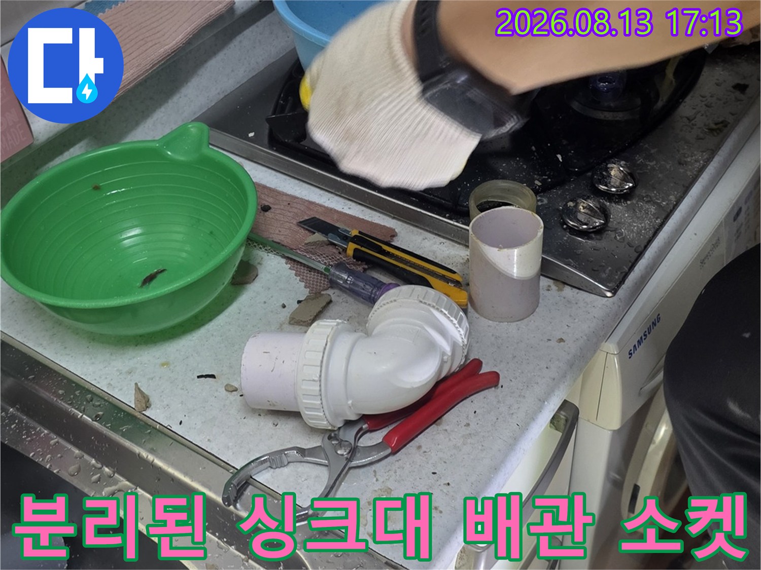 싱크대 하부장 아래의 분리된 흰색 배관 부품과 작업 도구