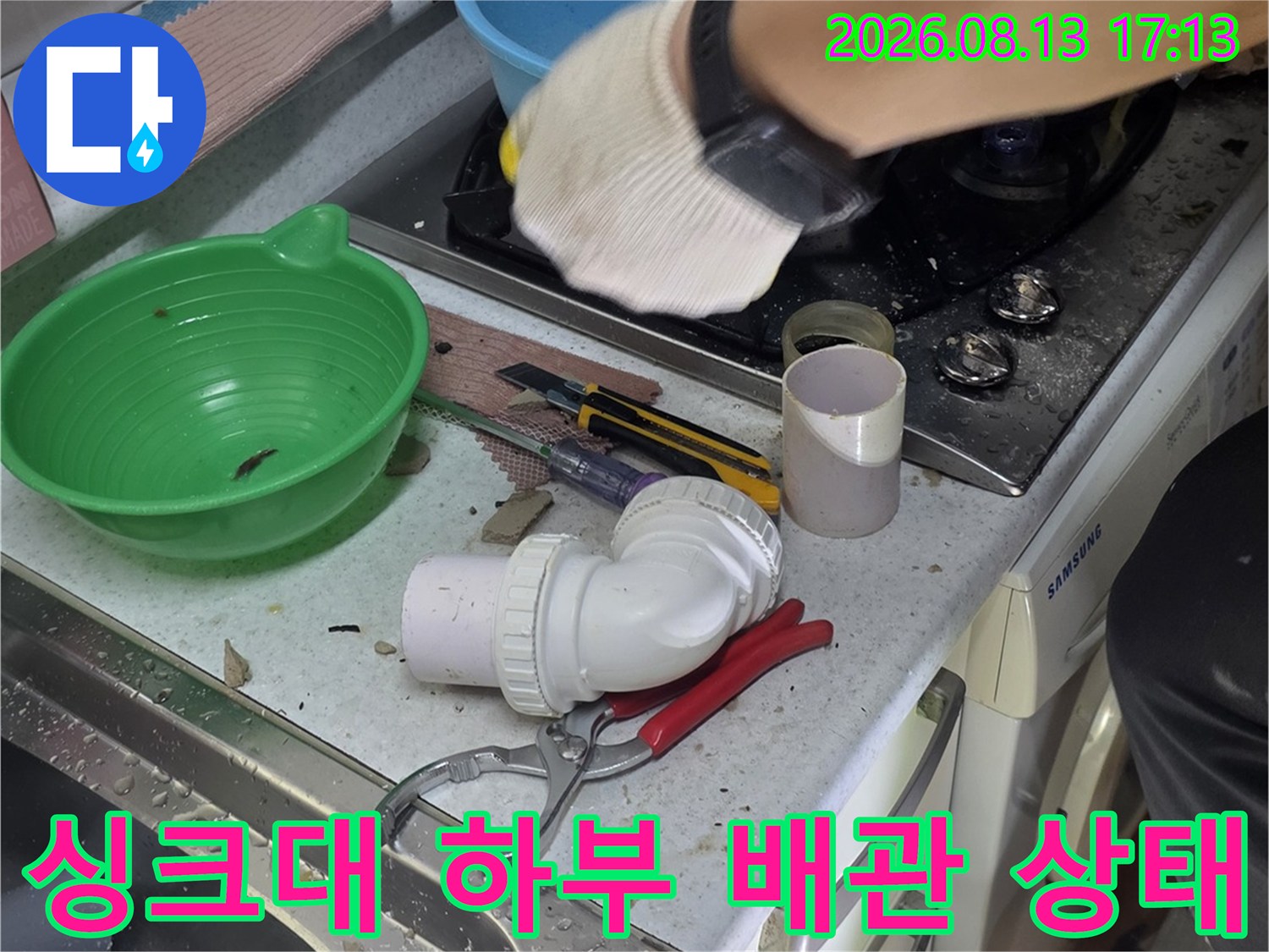 철산동 싱크대 하부장 내부의 노출된 배관과 작업 도구들