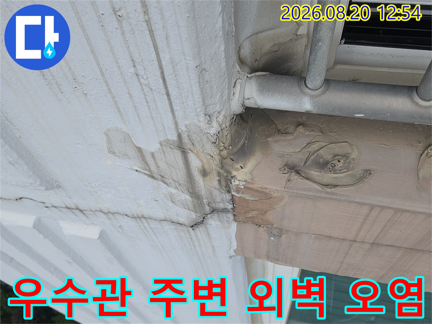 우수관 배관 근처 외벽의 젖은 얼룩과 균열