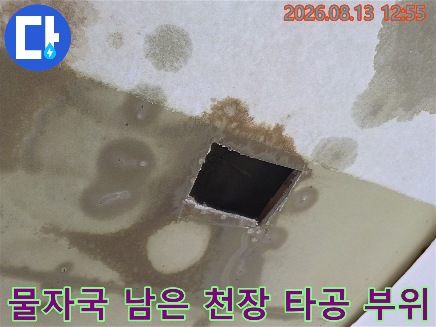 심하게 오염된 천장 마감재 중앙에 내부 점검을 위한 사각 구멍이 뚫려 있음