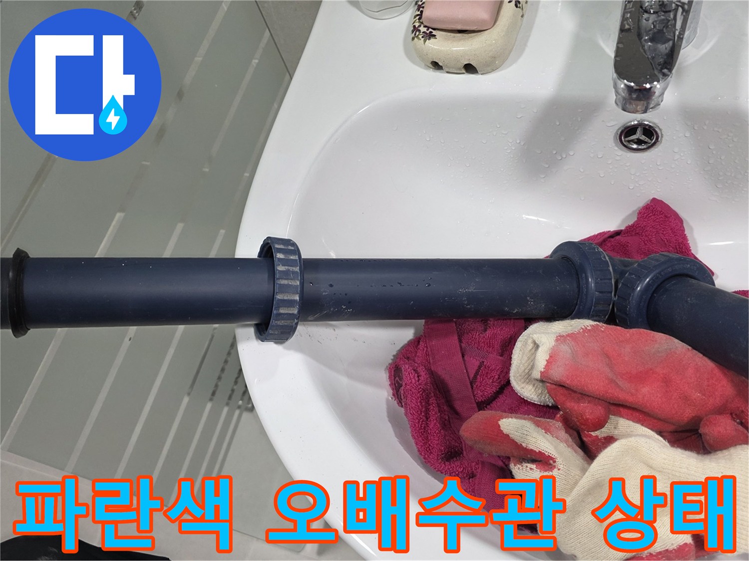 세면대 밑 파란색 배관과 작업 도구 사진입니다.