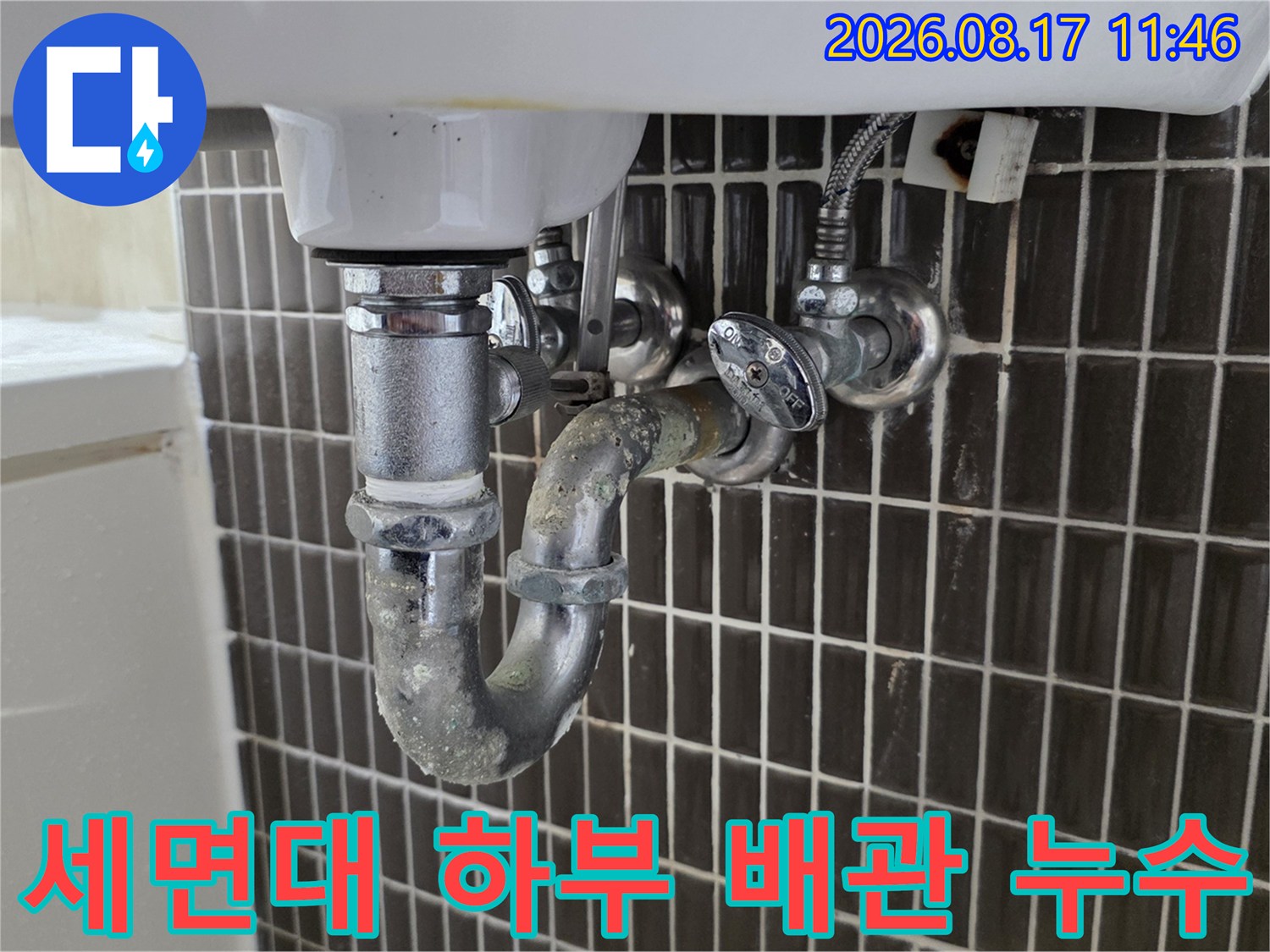 세면대 밑으로 연결된 금속제 배관과 밸브의 근접 사진입니다.