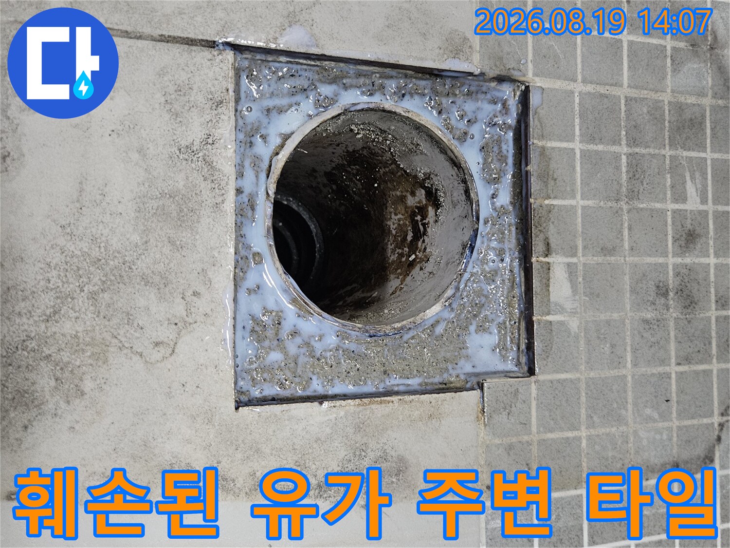 유가 주변의 훼손된 타일과 노출된 배관 입구를 보여줍니다.