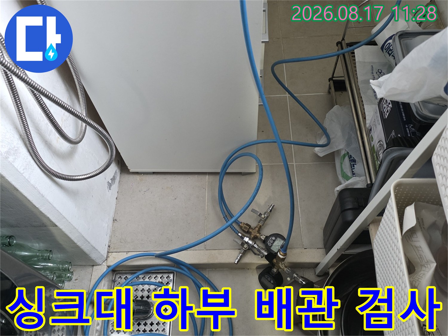 주방 싱크대 하부 배수구와 파란색 공압 호스 연결 모습