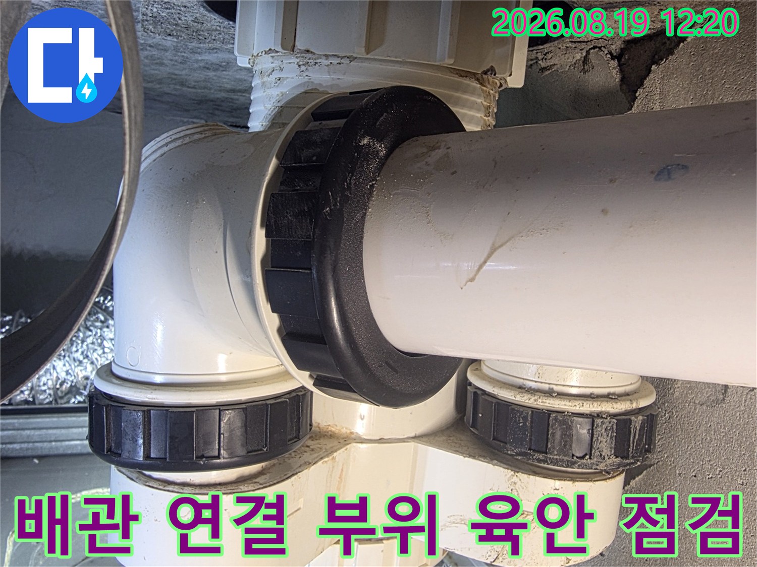하얀색 배관과 검은색 유니온-배관의 체결 상태를 면밀히 조사하는 사진입니다.