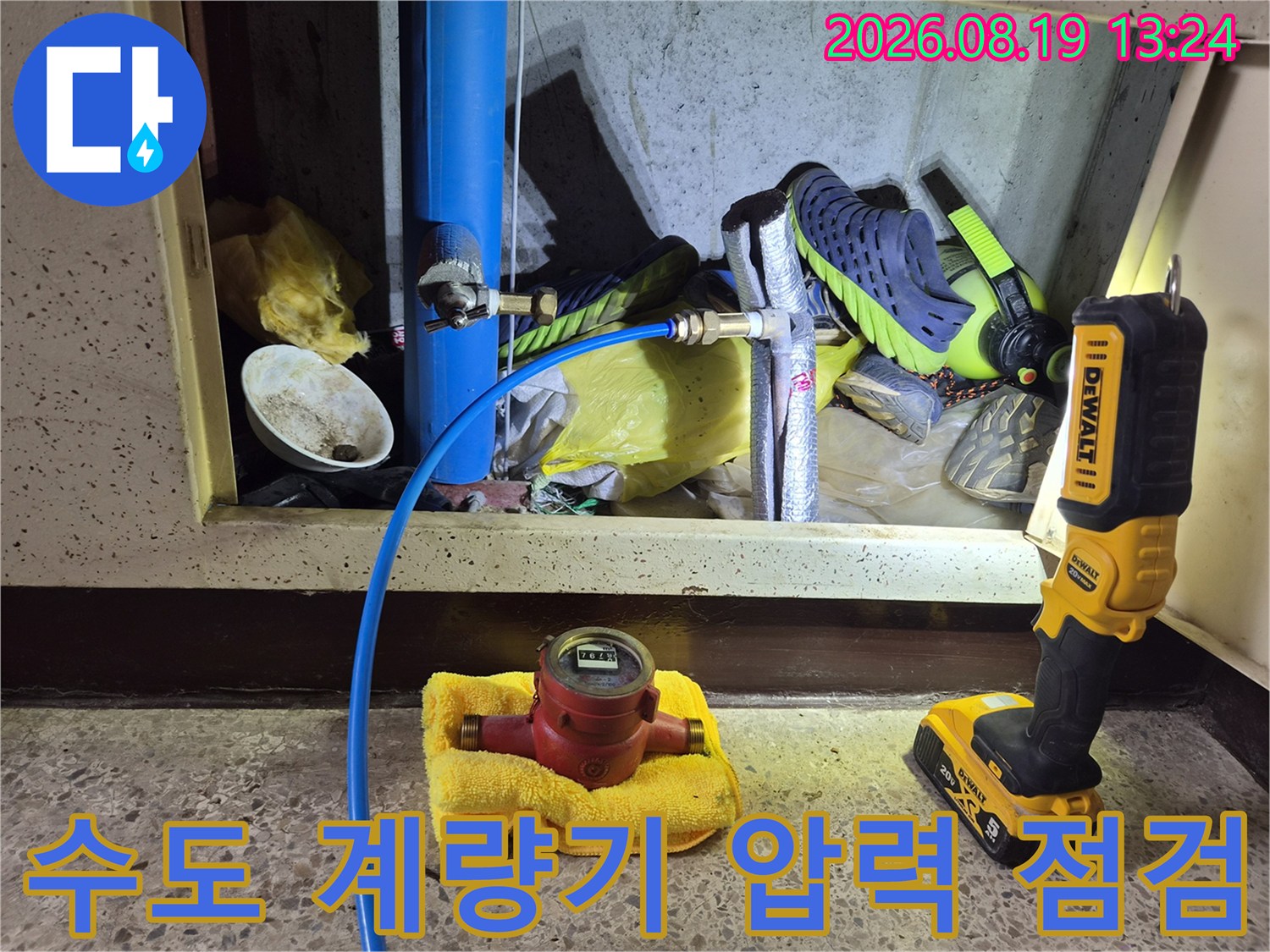 노란색 수건 위에 놓인 수도 계량기와 파란색 배관의 상세 모습입니다.