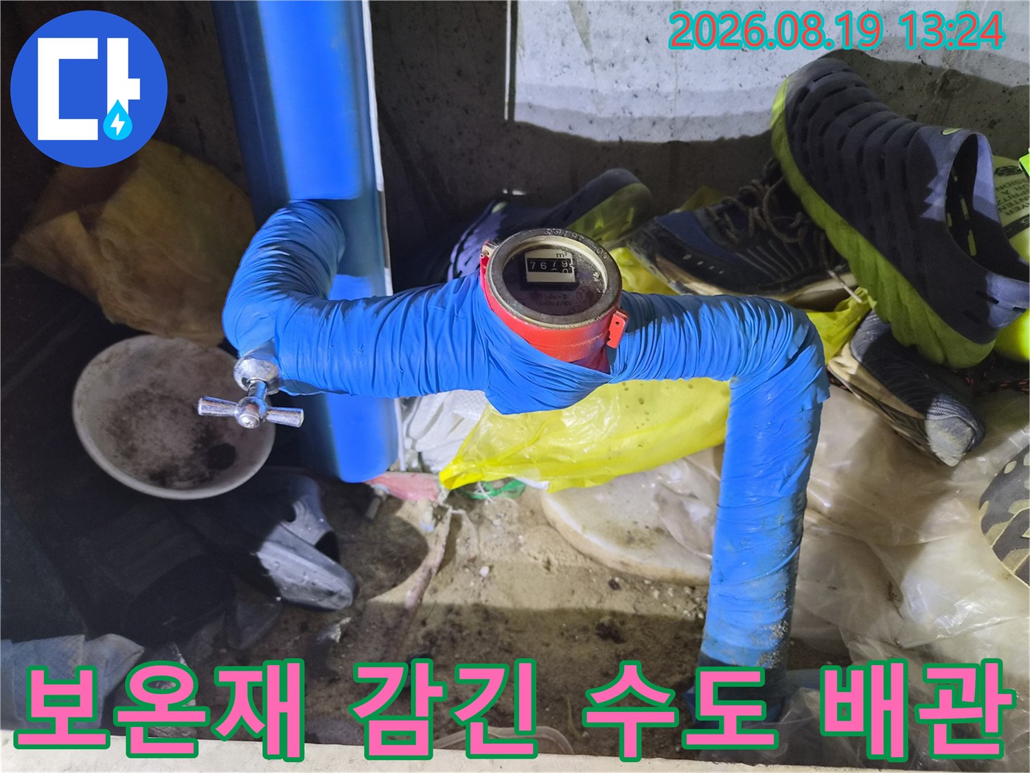 파란색 보온재로 마감된 배관과 작동 중인 수도 계량기