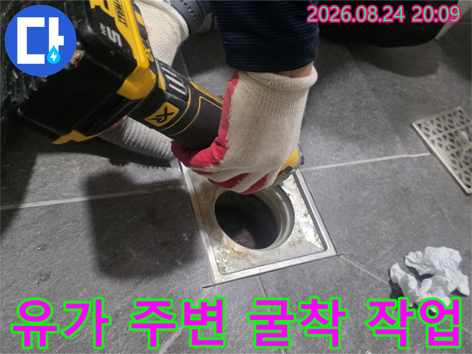 전동 드릴로 배수구 주변 타일을 조심스럽게 제거함