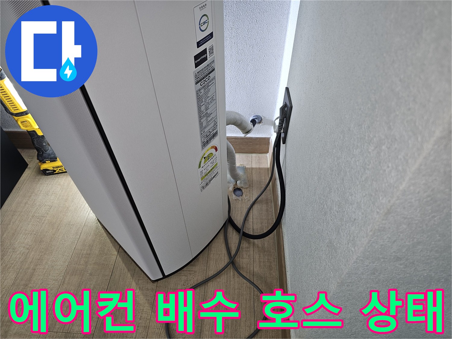 에어컨 본체 하단에서 나오는 드레인 호스의 연결 상태를 보여주는 사진입니다.