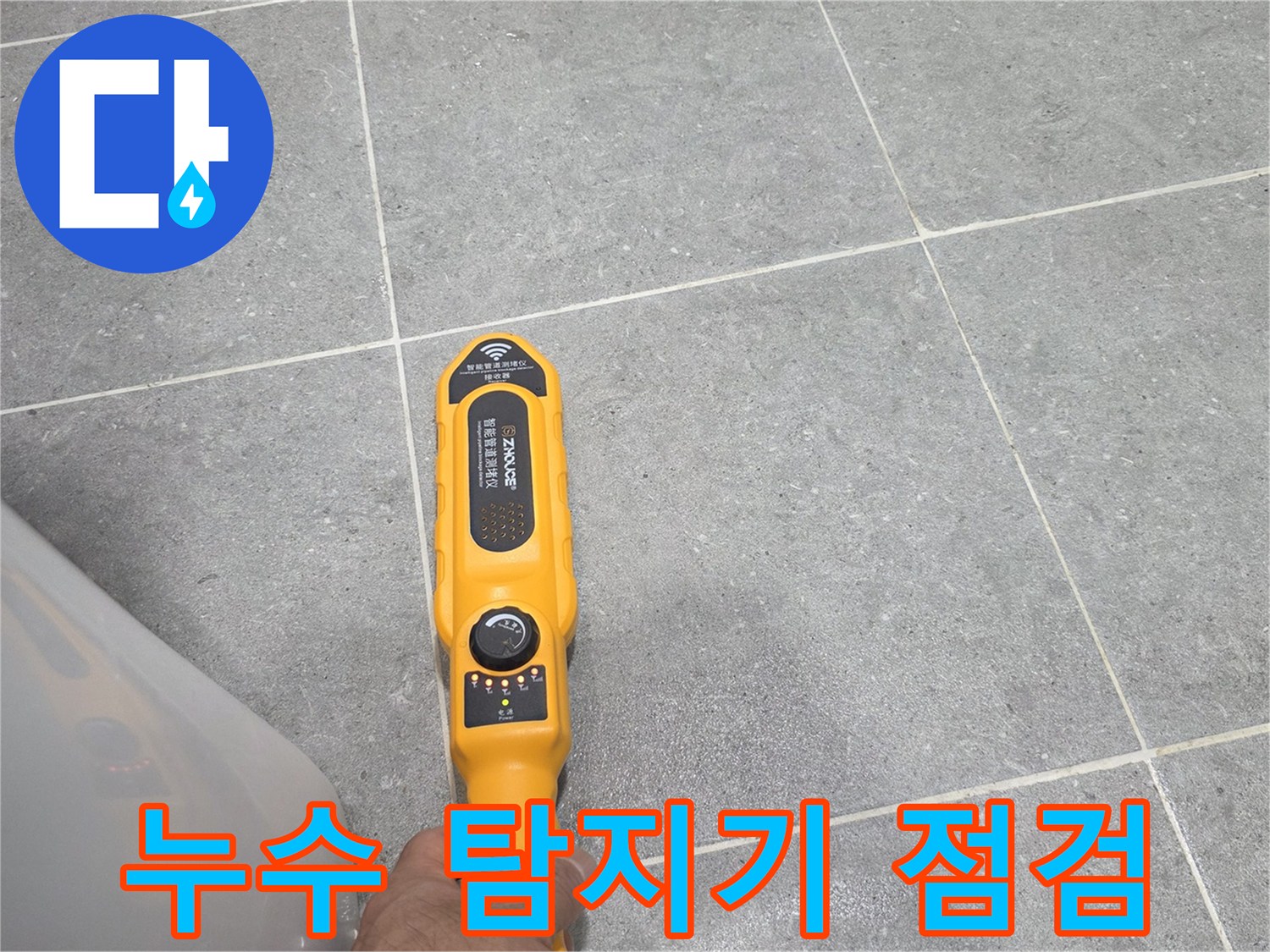 욕실 타일 위에서-누수 탐지 장비를 사용하여 바닥의 물샘 지점을 확인하는 모습입니다.