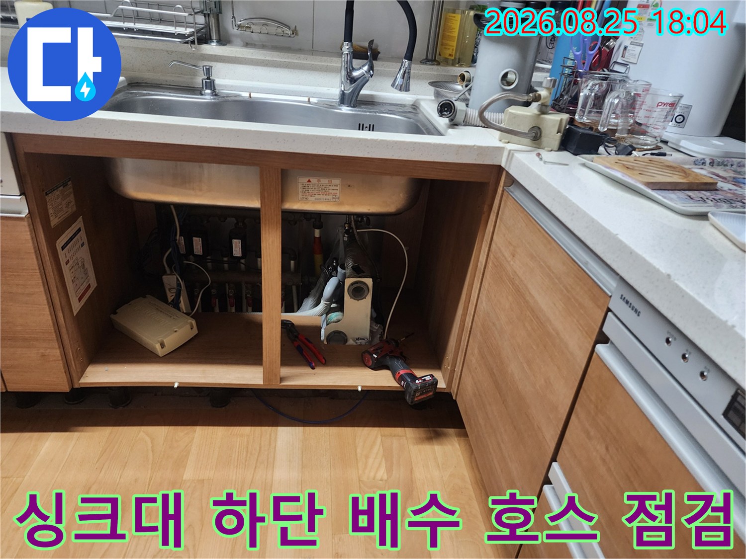 싱크대 아래 수납장 내부의 노출된 배관과 점검용 장비들