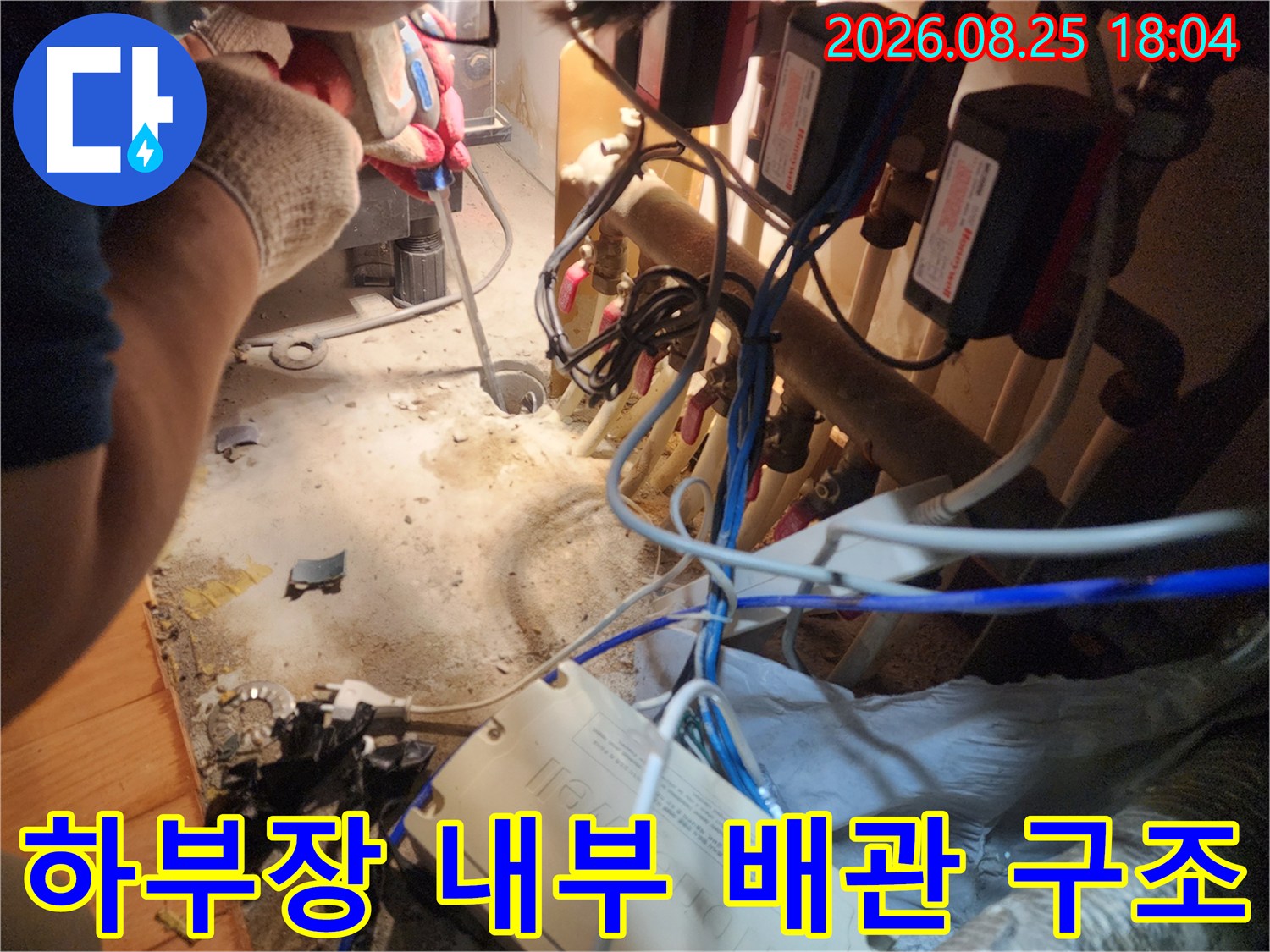 싱크대 하단 수납장 내부에 복잡하게 얽힌 배관과 장비들의 모습