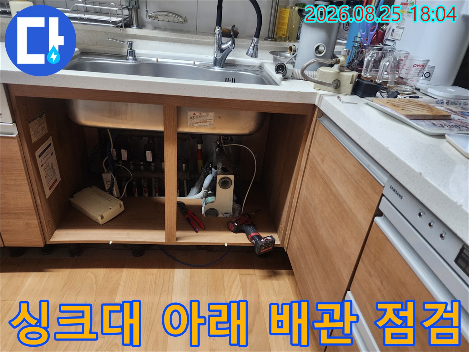 싱크대 하부장 내부의 배수 관로와 연결 부위를 상세히 촬영했습니다.