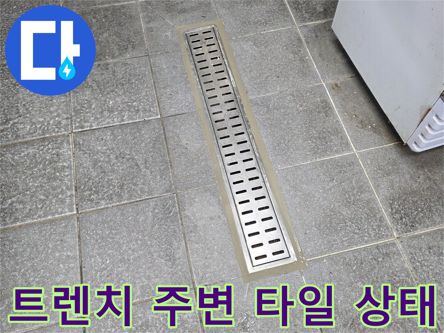 배수구 트렌치 덮개와 인접한 회색 타일 표면 상세 사진