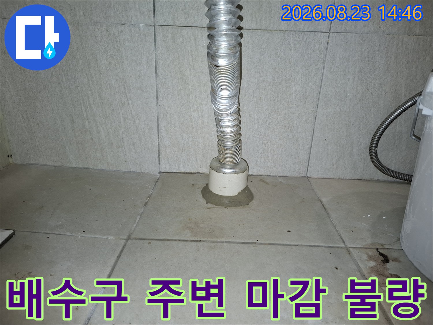 세탁실 배수구 하단 타일과 은색 배관의 접합부 모습