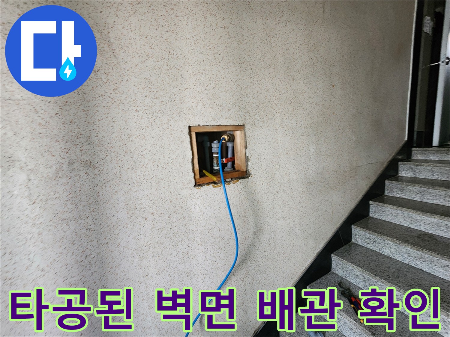 벽을 뚫어 노출시킨 배관과 연결된 파란색 호스