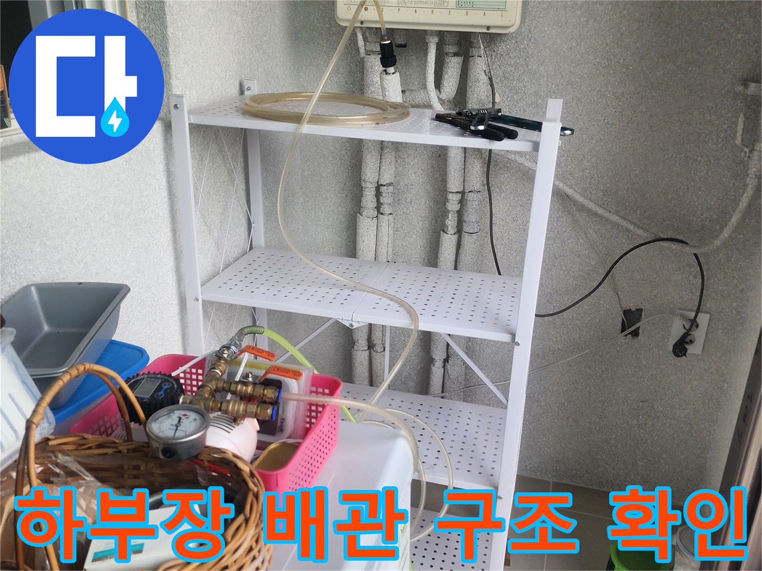 싱크대 하단 하부장 내부의 얽힌 배관과 점검용 압력계 장비