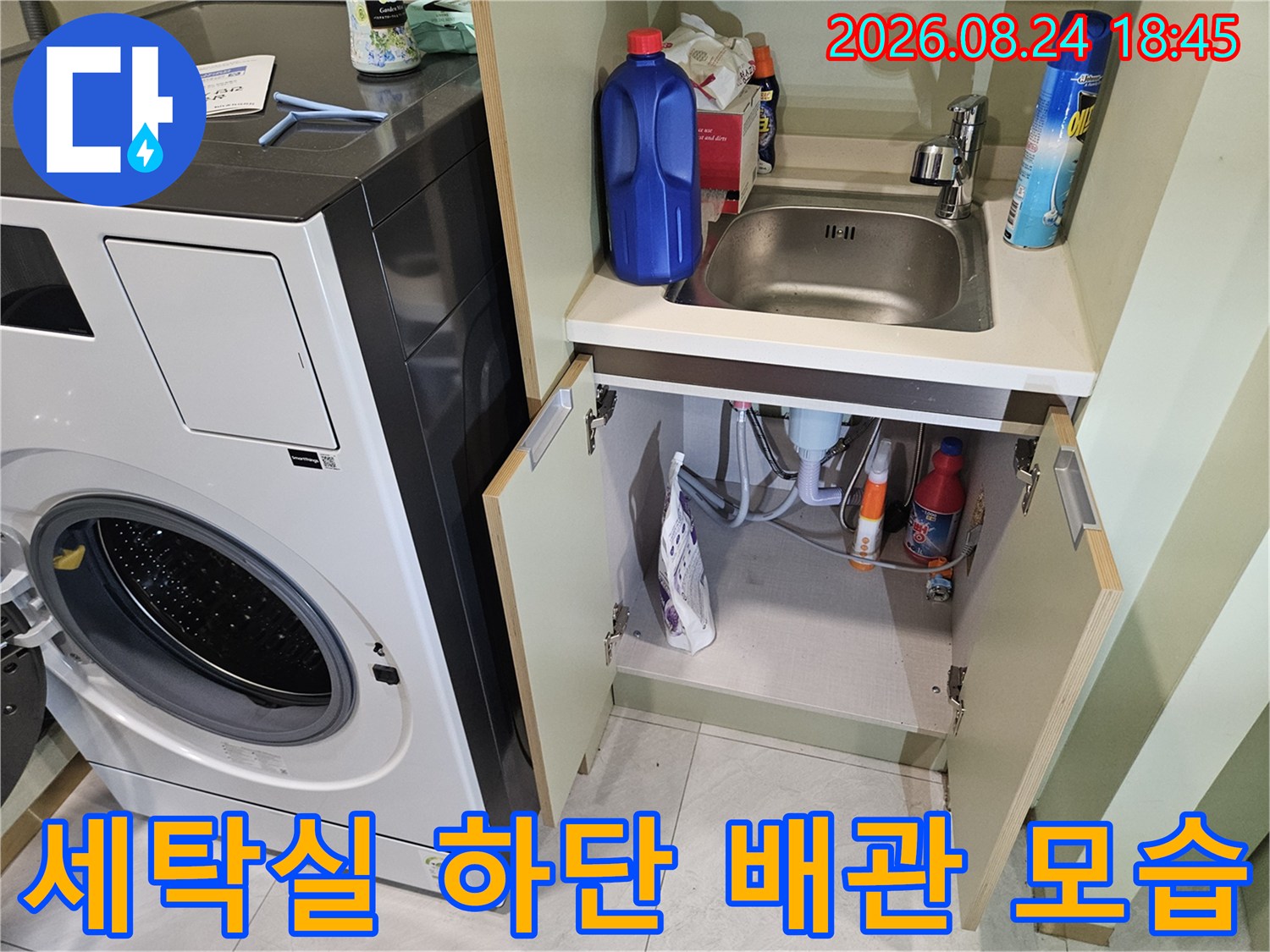 세탁기 주변 수납 공간의 세제 용기와 노출된 배수 호스들