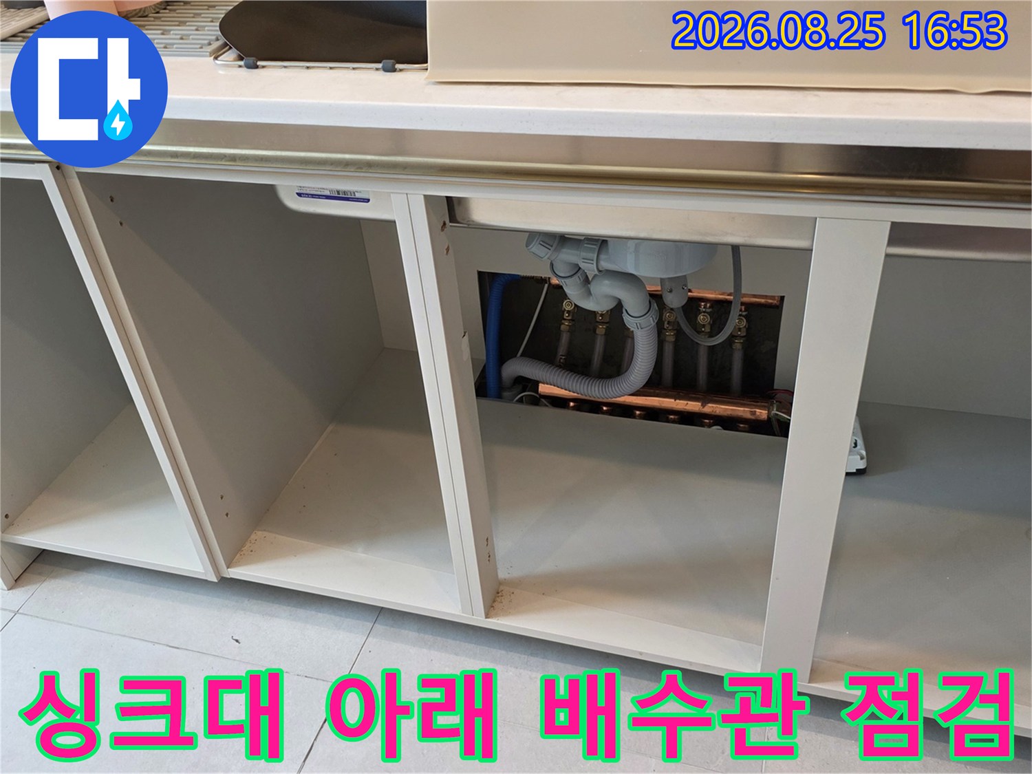 싱크대 밑 빈 공간에 위치한 하수 배관의 연결 상태를 촬영한 사진입니다.