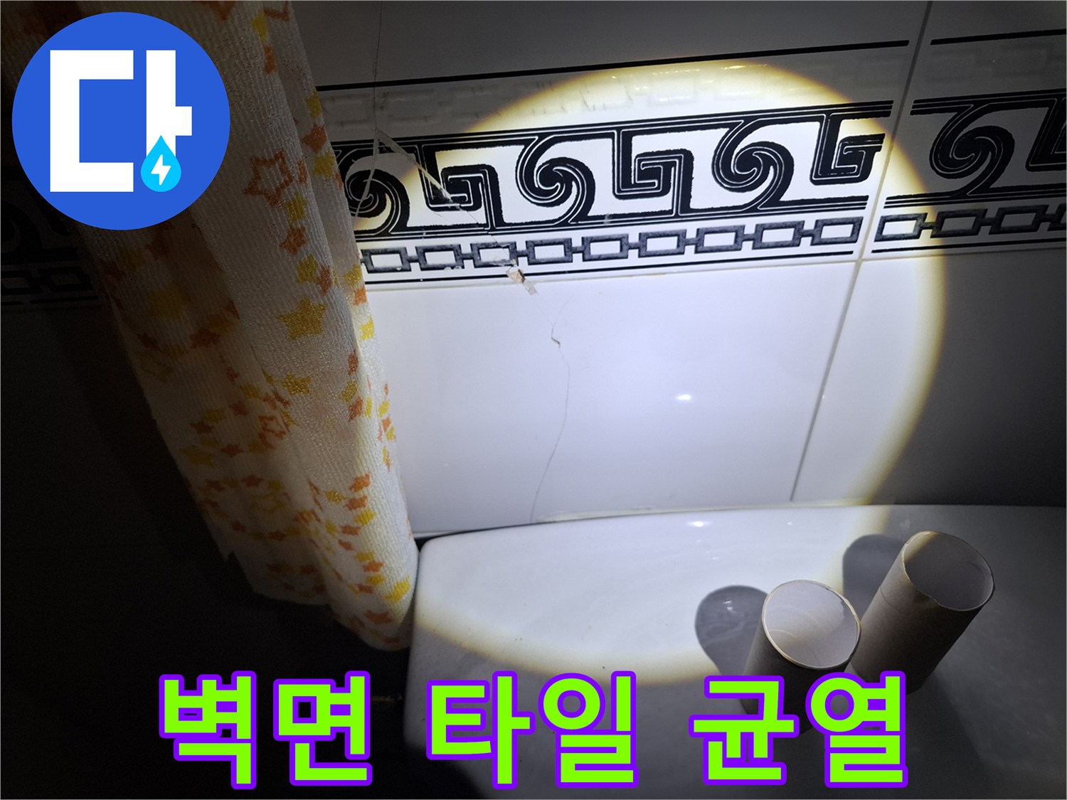 조명으로 밝힌 화장실 벽면의 세로 균열 부위