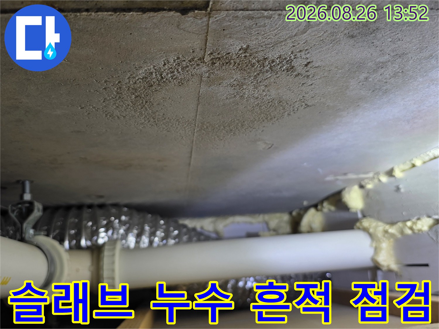 천장 슬래브에 넓게 퍼진 어두운 색상의 누수 오염 부위입니다.