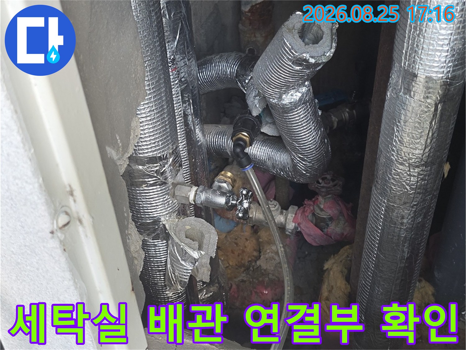 보온재로 덮인 배관과 금속 밸브가 설치된 배관함 내부의 모습입니다.