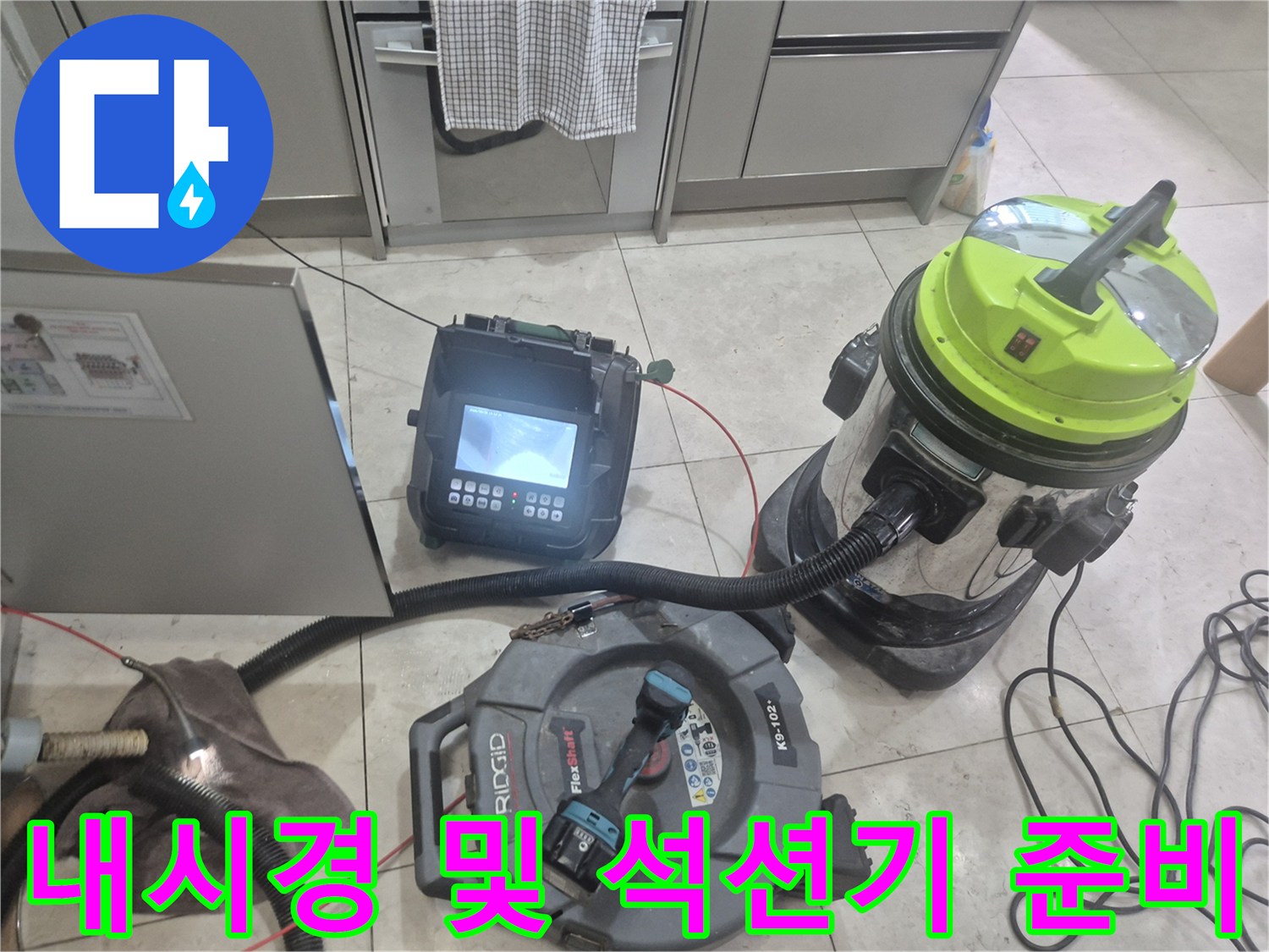 싱크대 하부 작업을 위해 배치된 내시경 장비와 석션 진공청소기