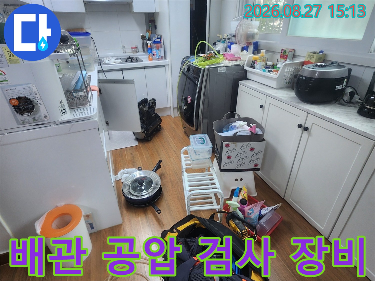 싱크대 하부장 근처에 놓인 배관 공압 검사용 전문 장비와 측정 도구들입니다.
