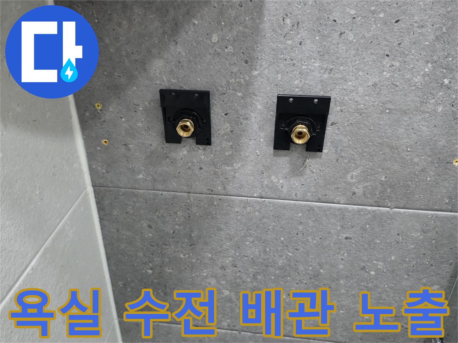 회색 타일 벽면에 노출된 해바라기 샤워기용 배관 연결 부위
