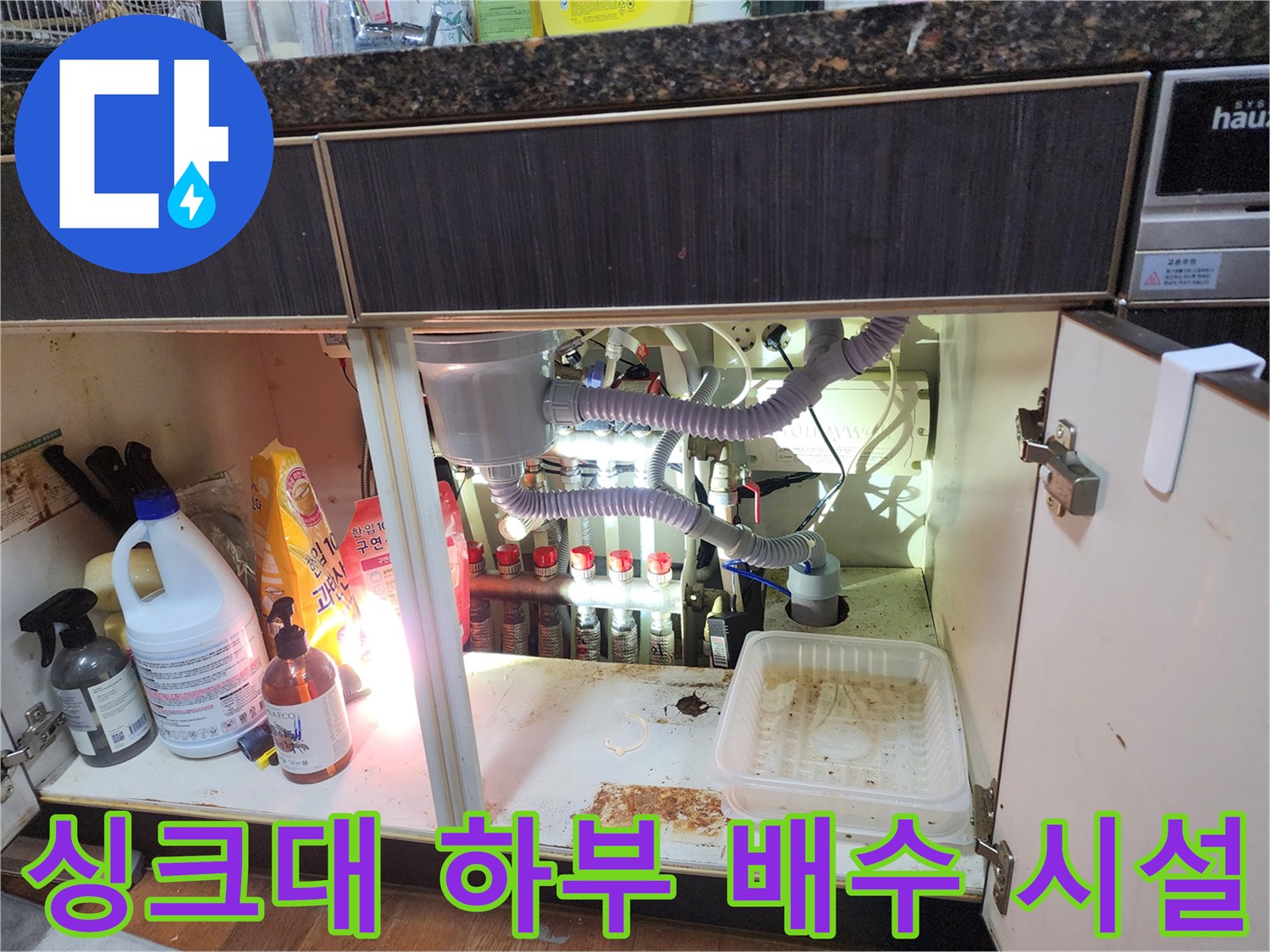싱크대 아래쪽 에어컨 배수 호스와 주변 세제통들