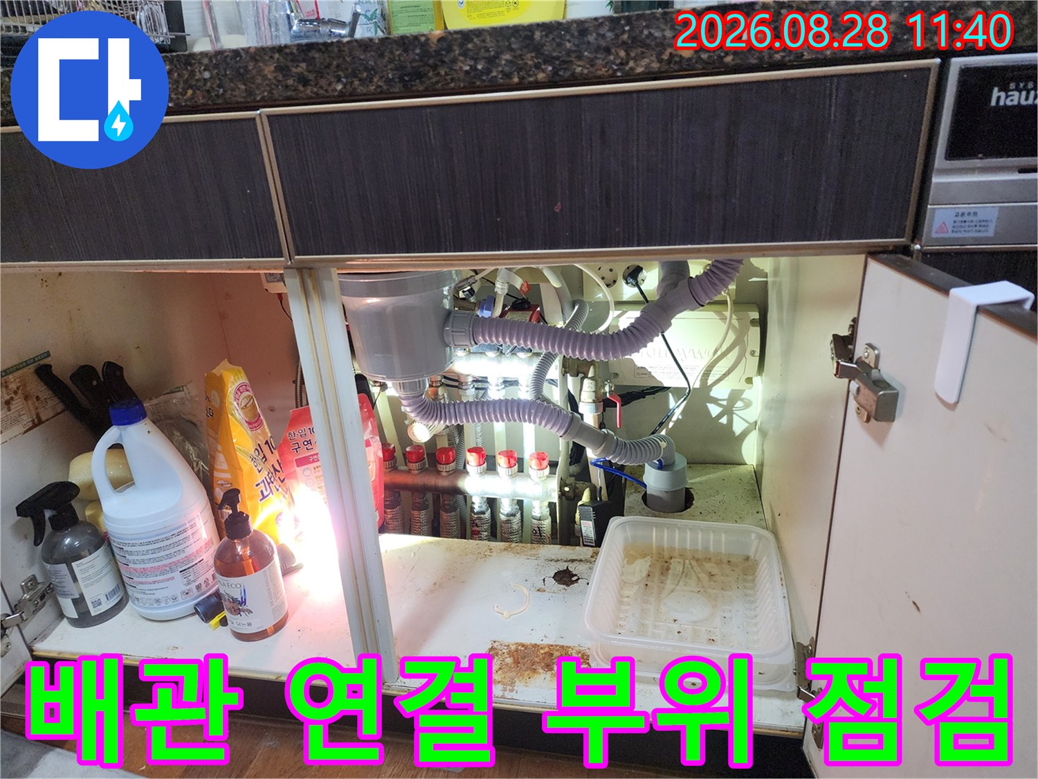 싱크대 하단 공간에 있는 에어컨 드레인 호스와 다양한 배관 구조