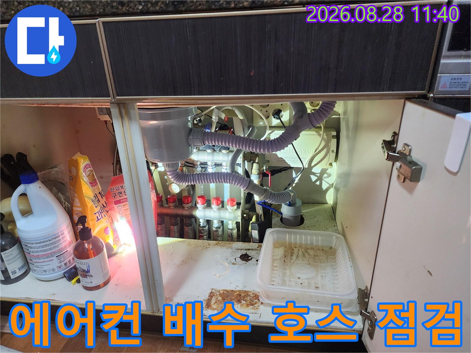 싱크대 하단부에 연결된 에어컨 드레인 호스와 배수 배관의 복잡한 구조