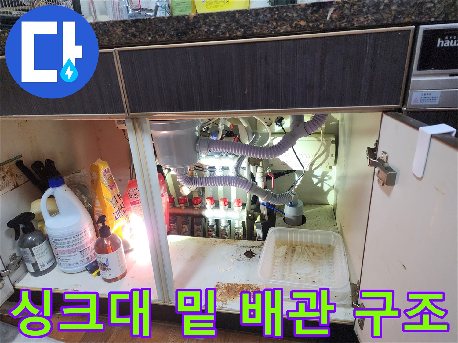 싱크대 하단장-내부의 복잡한 에어컨 배수 라인 및 연결 호스