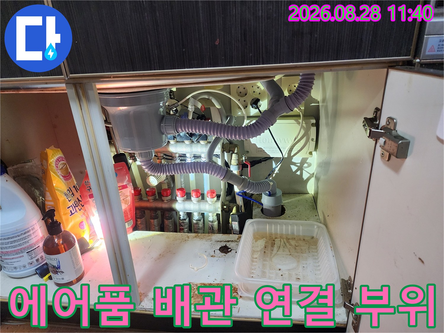 에어컨 드레인 호스와 정수기 필터가 복잡하게 연결된 싱크대 내부 배관