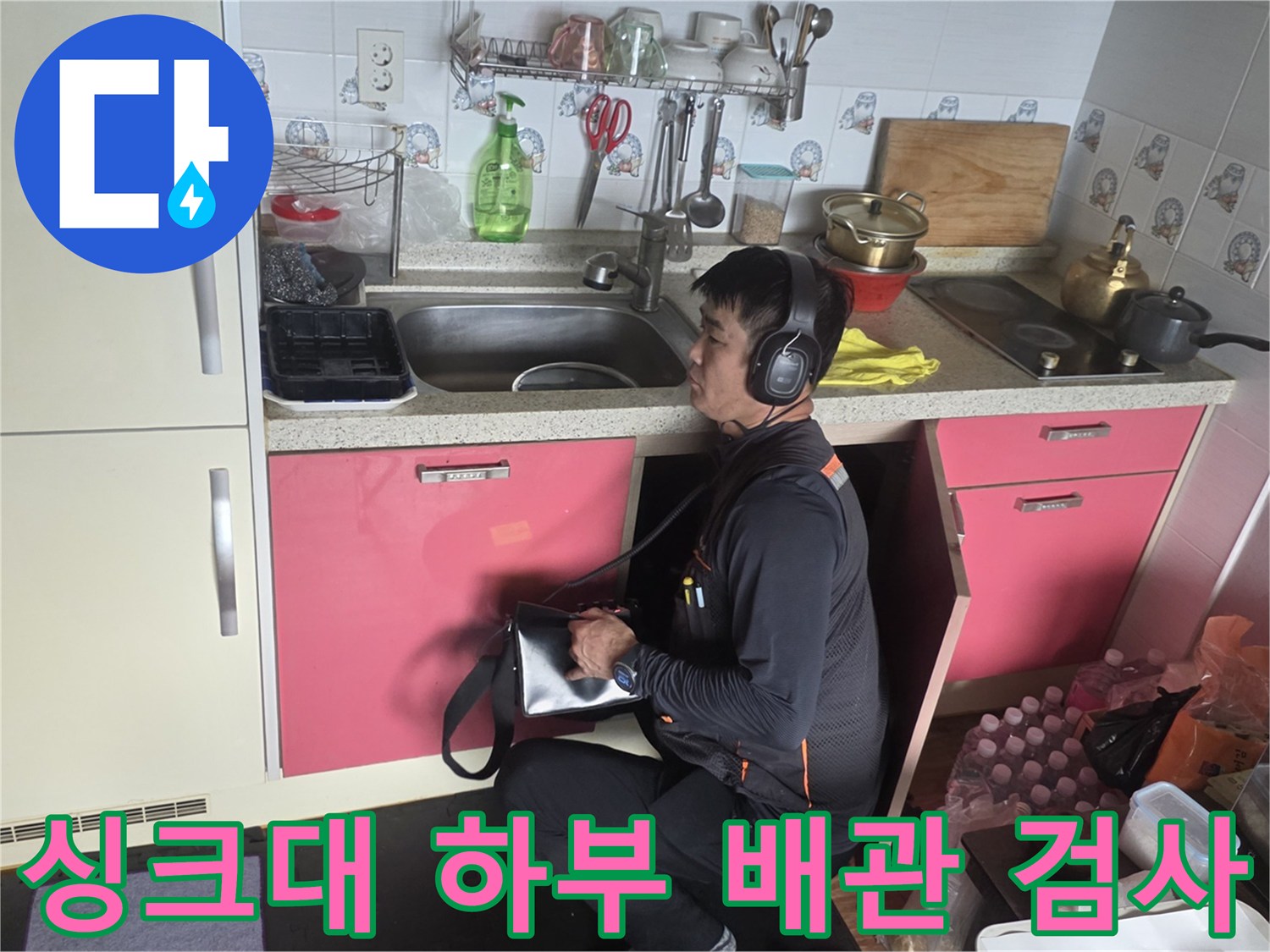 엔지니어가 청음 장비를 사용하여 싱크대 아래쪽 배관 상태를 면밀히 살핍니다