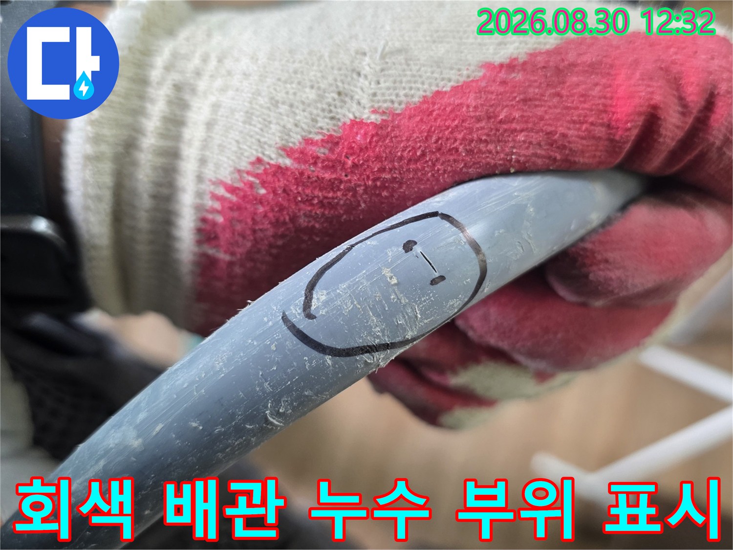 작업자가 손으로 잡고 있는-회색 배관의 누수 지점 표시