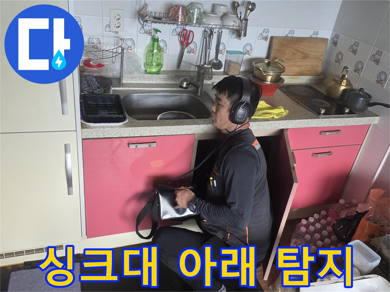 주방 싱크대 밑-누수 지점을 찾기 위해-청음기를 사용 중인 엔지니어