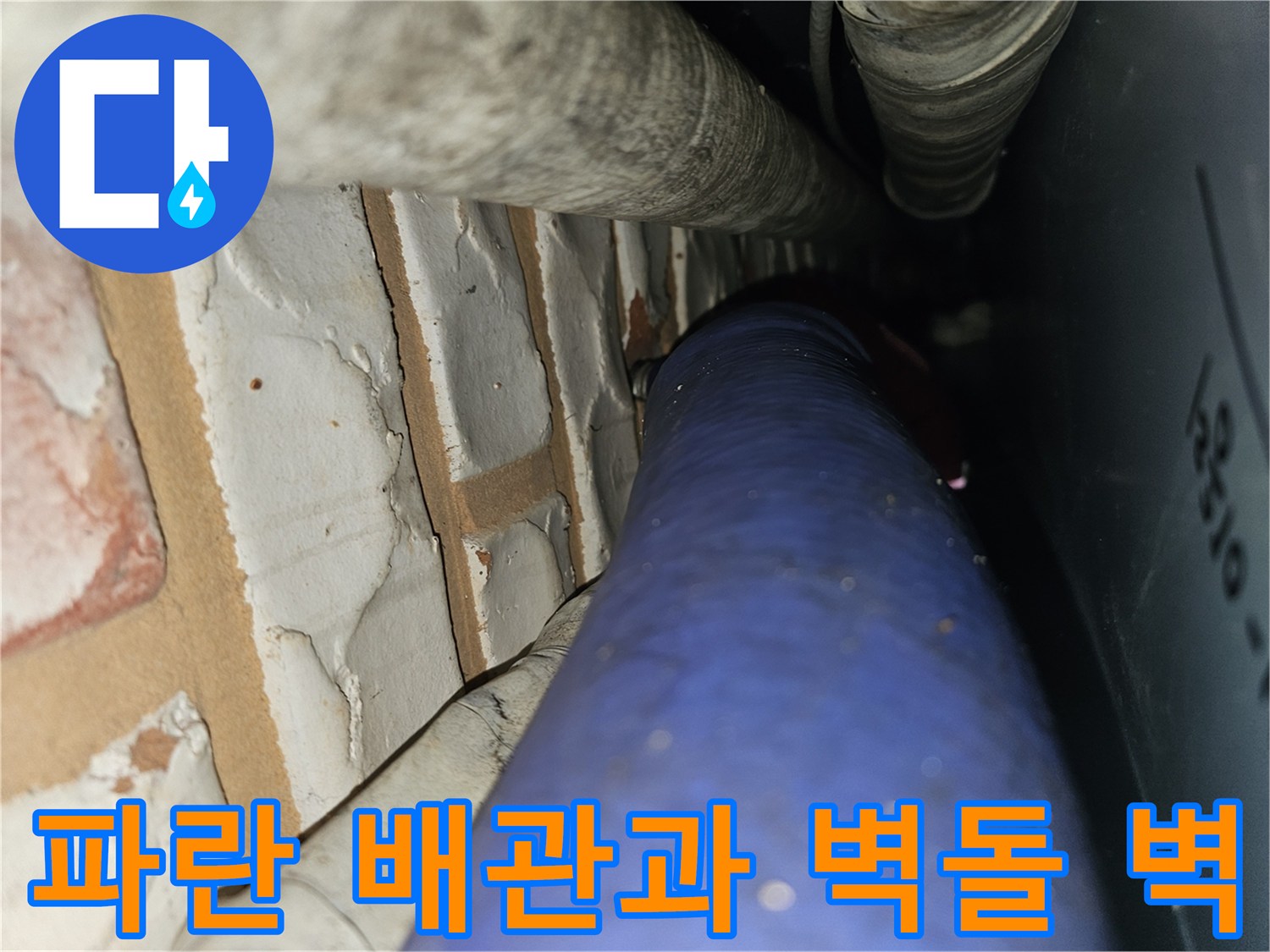 벽돌 구조물 옆에 설치된 파란색 수도 배관의 근접 촬영 사진