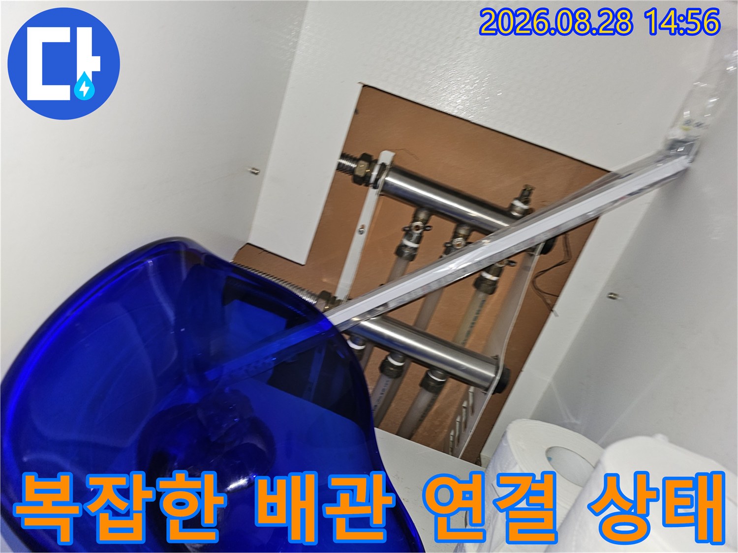 싱크대 하단에 노출된 보일러 배관의 복잡한 구조와 연결 상태를 보여줍니다.